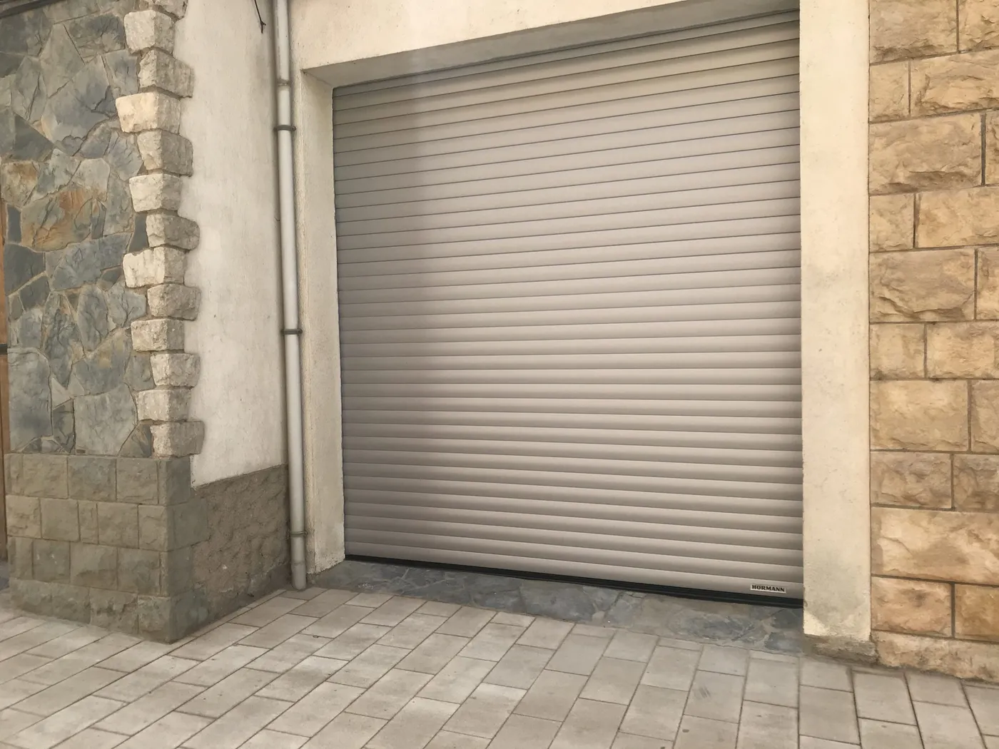 Porta de garatge enrotllable en una façana de pedra